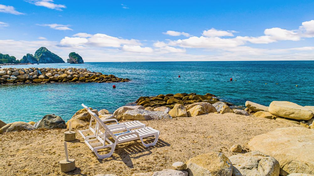 Loungers on the private beach with Los Arcos in the distance