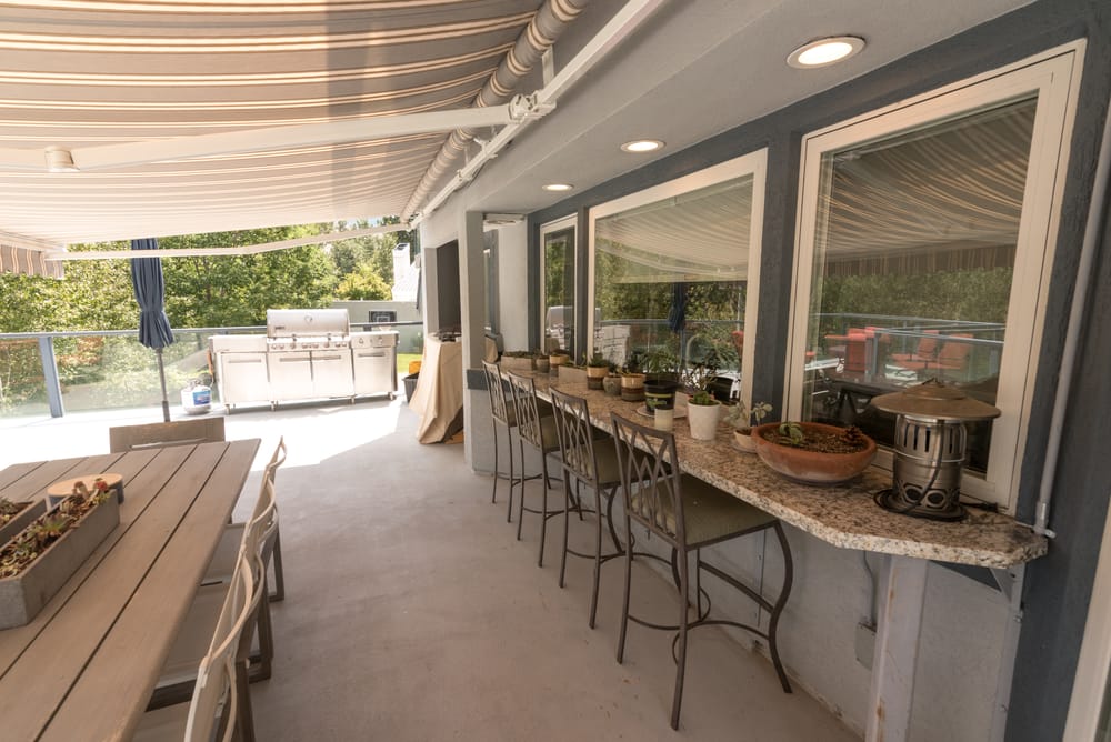 Covered deck bar with stools and outdoor kitchen