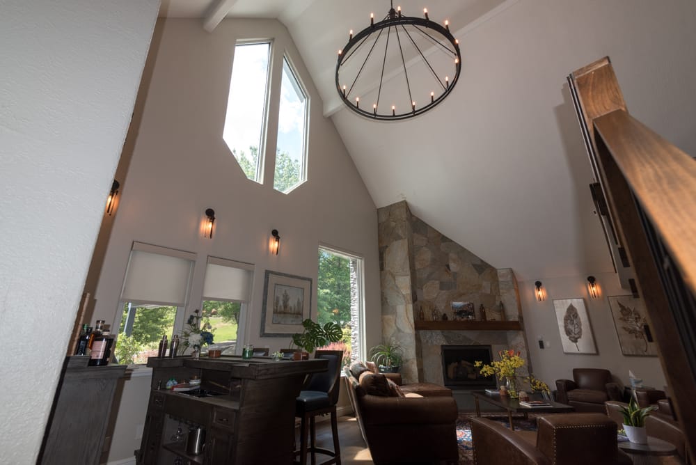 Vaulted great room with iron chandelier, tall windows and wet bar